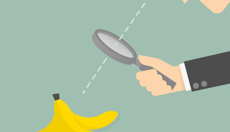 Businessman looking to a banana peel through a magnifying glass