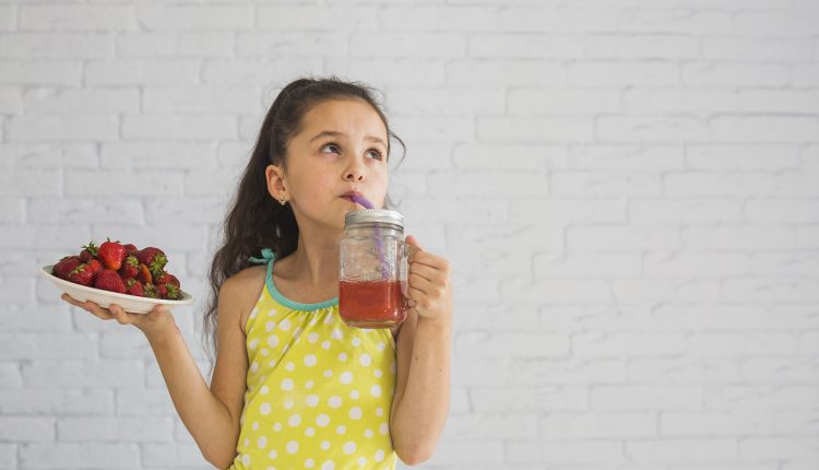 girl-holding-plate-red-strawberries-drinking-strawberry-smoothies