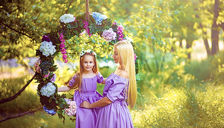 fashion outdoor photo of beautiful family look. beautiful mother with long dark hair posing with her little cute baby in similar dresses with flowers print