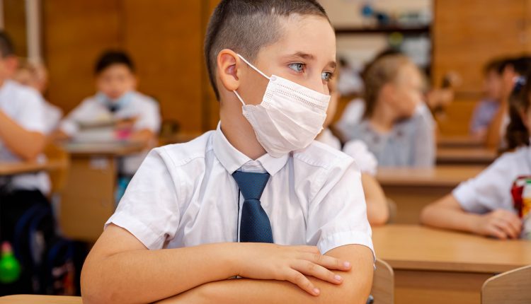 Child with face mask back at school after covid quarantine, lockdown