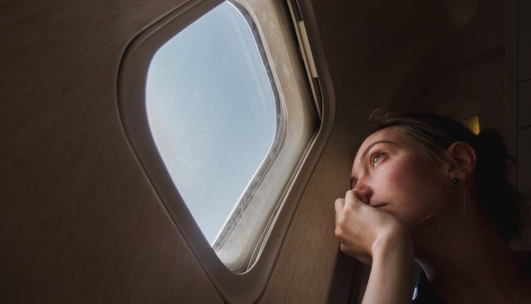 Sad woman at porthole in plane