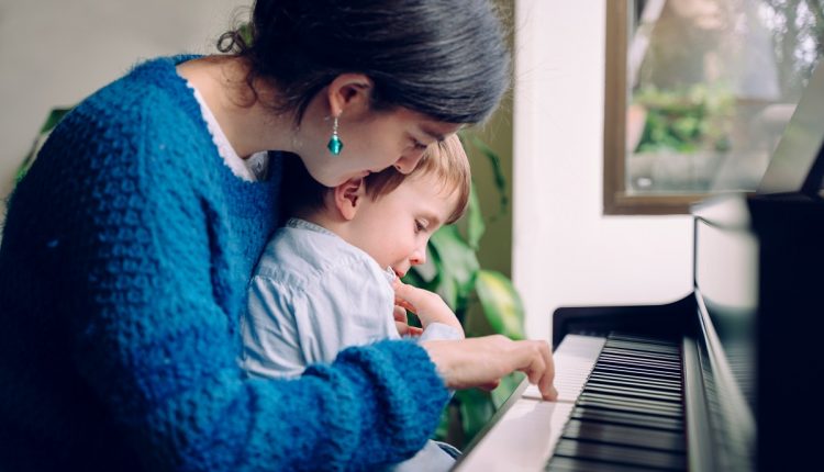 Mom teaching her son at home piano lessons. Family lifestyle spe