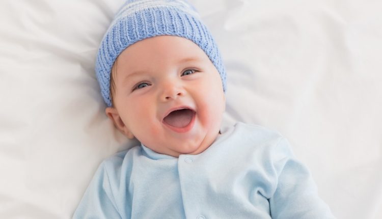 High angle portrait of cheerful baby boy in bed
