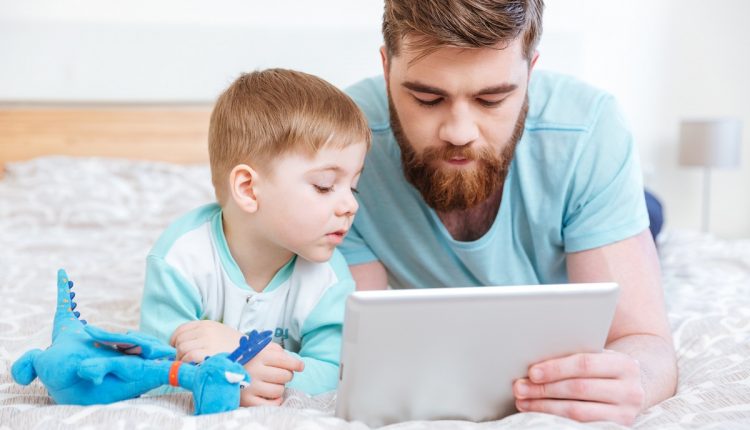 Dad and son using tablet together at home