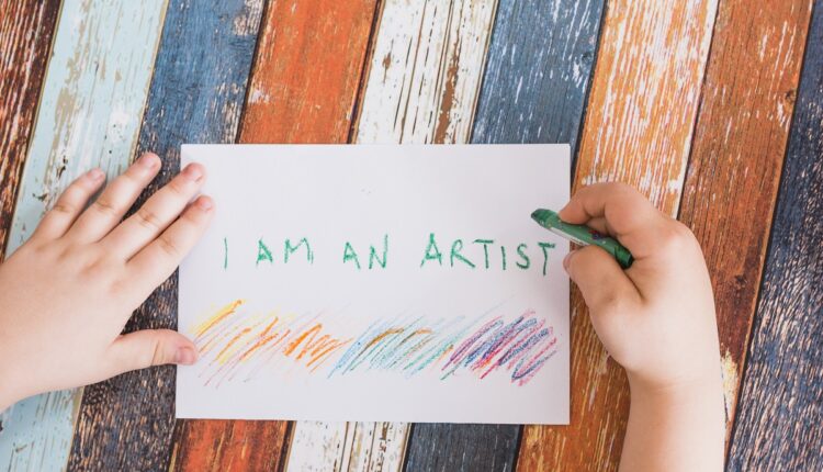 person-s-hand-writing-white-paper-with-green-crayon-weathered-wooden-desk
